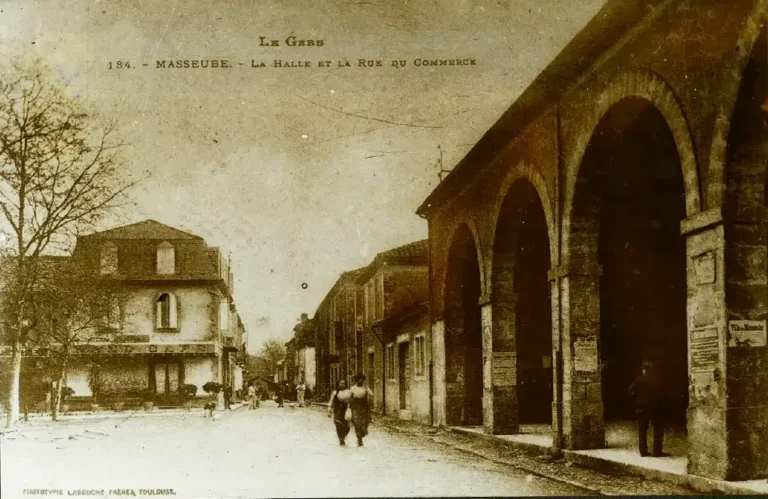 Photo ancienne de la halle rue du commerce avec le café au coin à Masseube